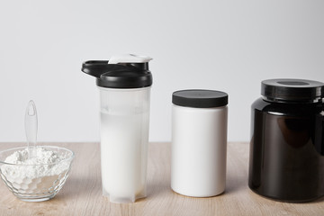 protein shake in sports bottle near jars isolated on grey
