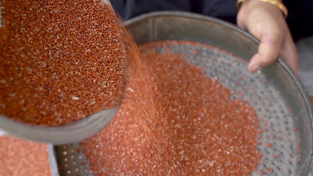 pouring ragi grains into the filtering bowl for cleaning
