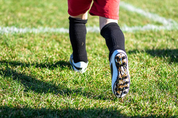 blurred for effect - action shot of young kid in cleats running onto soccer field