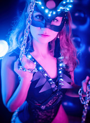 Fototapeta premium A girl in a sexy cat and party costume posing in a neon set for Halloween