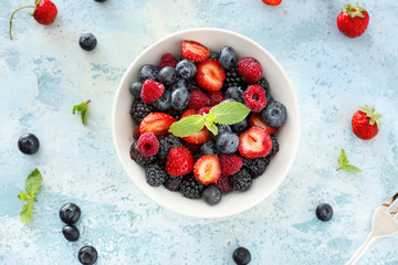 Bowl with tasty berry salad on color background