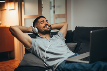 man relaxing in sofa at his apartment listening to music