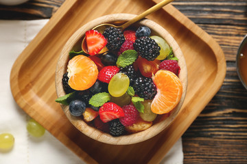 Bowl with tasty fruit salad on table