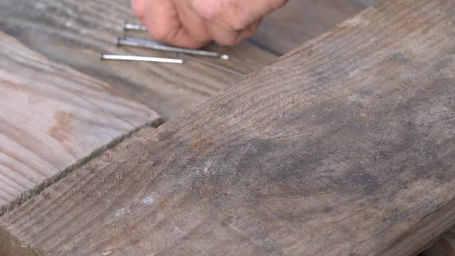 Man hammering nail into board hammer. Hands of an elderly man, the old hammer and nail. Close up. Detail of worker with a nail and a hammer