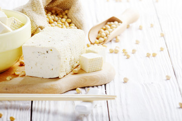 Soy Bean curd tofu in clay bowl and in hemp sack on white wooden kitchen table. Non-dairy alternative substitute for cheese. Place for text