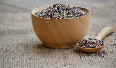 Quinoa grain in wood bowl with spoon on wooden background