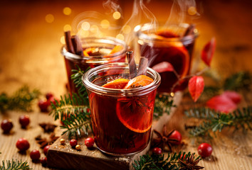 Boże Narodzenie grzane czerwone wino z aromatycznymi przyprawami i owocami cytrusowymi na drewnianym wieśniaka stole, zakończenie. Tradycyjny gorący napój w czasie świąt Bożego Narodzenia - 296546152