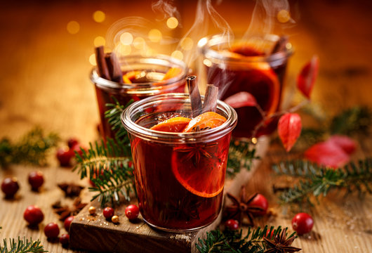 Christmas mulled red wine with aromatic spices and citrus fruits on a wooden rustic table, close-up. Traditional hot drink at Christmas time