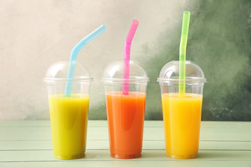 Plastic cups of fresh juice on table