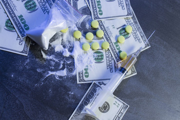 cocaine, dollars, pills and syringe on the table