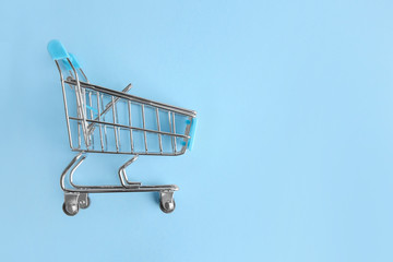 Empty small shopping cart on color background © Pixel-Shot