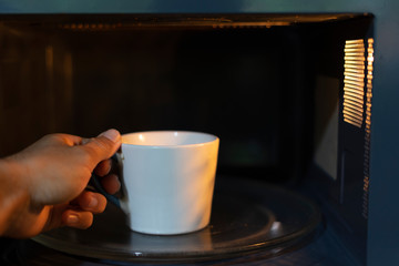 Warming up a drink with a microwave oven.