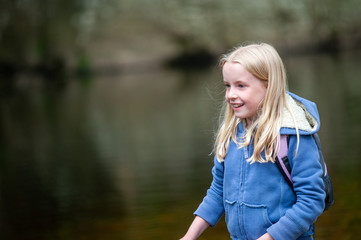 Smiling young blonde girl with out of focus river scene in background