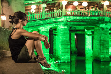 Fototapeta na wymiar Hoi An, Vietnam »; August 2017: A European brunette on the Japanese Covered Bridge in the city of Hoi An illuminated at night in green