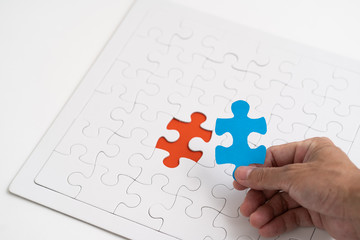 Hand holding blue piece jigsaw with red hold jigsaw background