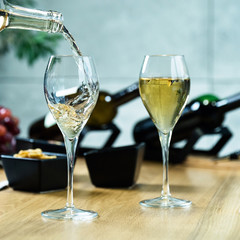 Pouring white wine into the glass against wooden table