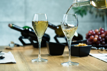 Pouring white wine into the glass against wooden table