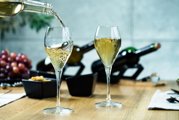 Pouring white wine into the glass against wooden table