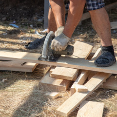 A worker cuts a wooden board at a construction site