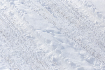 Traces of a car on white snow as a background