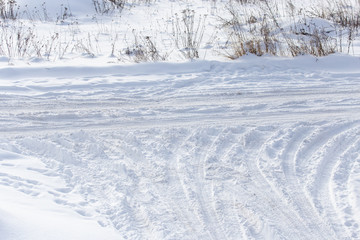 Traces of a car on white snow as a background