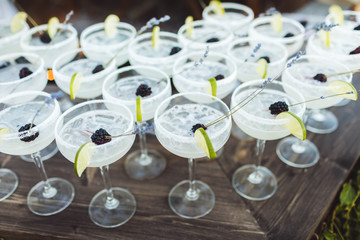 Set of Margarita cocktails with slice of lime and blackberry on top on bar counter. Evening patry, wedding reception