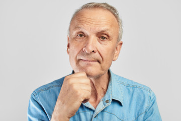 Portrait of a stylish modern elderly man on a white background in the studio. Senior boss thinking in a pensive pose