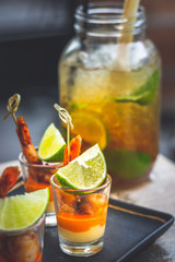 Classic cuban mojito with lime, mint and black sugar served in a big glass and prawn skewer tapas