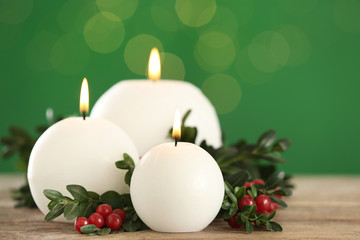 Beautiful Christmas composition with burning candles on table against green background