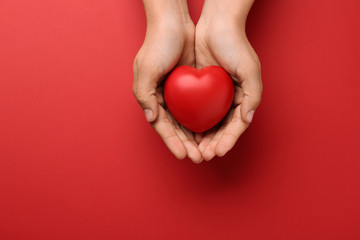 Woman holding decorative heart on red background, top view