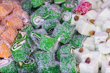 The oriental sweet in Turkish pleases with red, green and white rolls with nuts and coconut. Closeup of turkish sweets, selective focus.