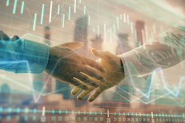 Double exposure of financial graph on cityscape background with two businessman handshake. Concept of stock market deal