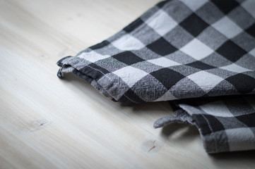 Checked black and white kitchen towel on wooden surface. Selective focus 