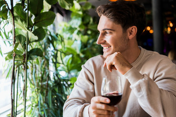 happy man holding glass with red wine in restaurant