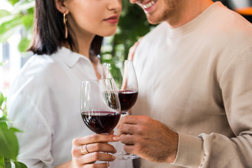 cropped view of happy man holding glass with red wine near girl