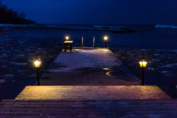 night winter seascape with a pier with cold lights