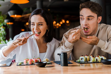 young man and woman eating tasty sushi in sushi bar
