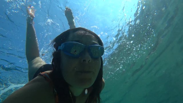 Kekova, Turkey - 30th of September 2019: 4K Front selfie Woman makes a roll over back underwater