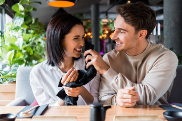 happy man holding black napkin near face of smiling woman