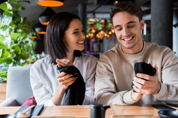 cheerful man and happy woman holding black napkins in sushi bar