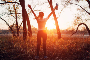 Runner raised arms after workout feeling free and happy succeeded in training. Woman admiring sunset.