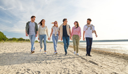 friendship, leisure and people concept - group of happy friends walking along beach in summer - Powered by Adobe