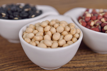 navy beans, cowpeas and black beans in ceramic cup on wooden background
