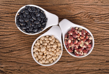 top view navy beans, cowpeas and black beans in ceramic cup on wooden background