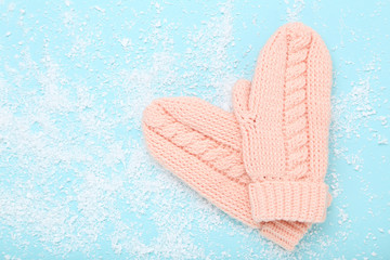 Knitted mittens with white snow on blue background