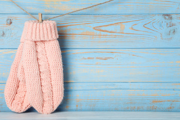 Knitted mittens hanging on blue wooden background