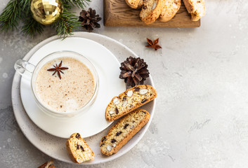 Fototapeta na wymiar Eggnog. Christmas milk cocktail with cinnamon and anise, served in glass mug with biscotti, winter spices, fir branches and cones.