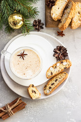 Eggnog. Christmas milk cocktail with cinnamon and anise, served in glass mug with biscotti, winter spices, fir branches and cones.