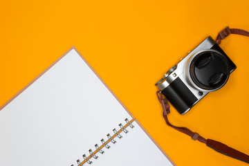 Travel concept with camera and note on orange background