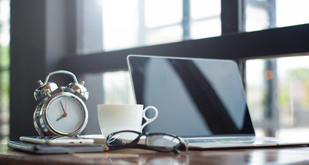 Working desk with laptop and coffee cup early in the morning.